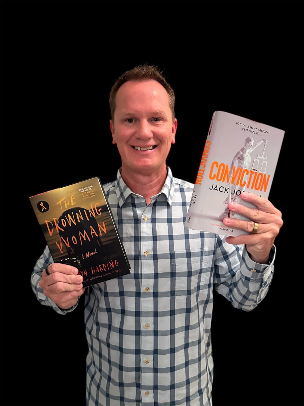 Michael Norris of I Heart A Good Thriller holding two thrillers — The Drowning Woman by Robyn Harding and Conviction by Jack Jordan